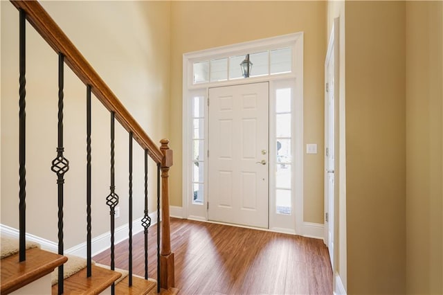 entrance foyer with stairway, baseboards, and wood finished floors