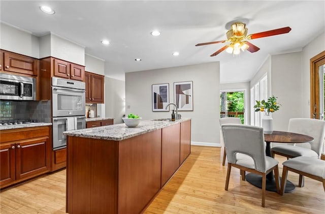 1075 Winding Branch Ln, Atlanta, GA 30338 - kitchen with stainless steel microwave, double oven, a sink, a ceiling fan, and light wood-style flooring