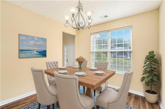 dining room featuring a notable chandelier, dark wood finished floors, visible vents, and baseboards