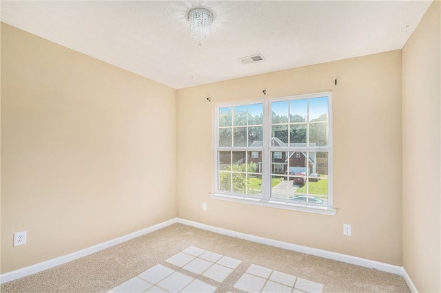 spare room with carpet, visible vents, and baseboards