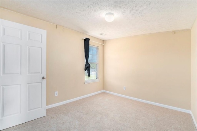 spare room with light carpet, a textured ceiling, and baseboards