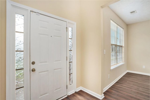 entryway with dark wood-type flooring, visible vents, and baseboards