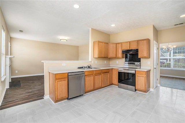 kitchen featuring a sink, visible vents, light countertops, appliances with stainless steel finishes, and range hood