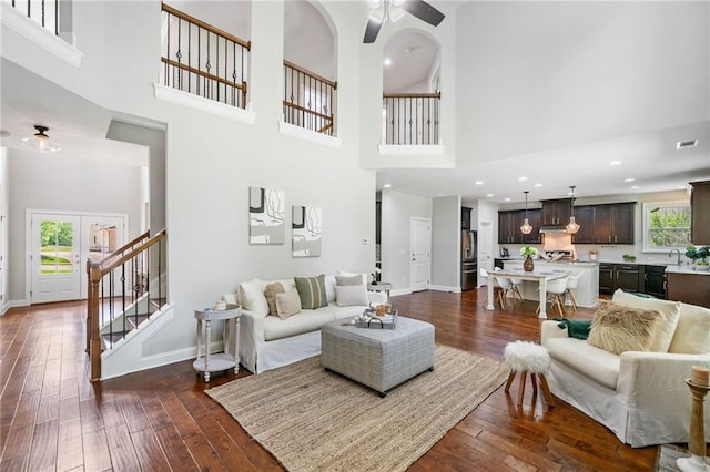 4460 Hunters Walk Way, Cumming, GA 30028 - living room with a ceiling fan, a high ceiling, dark wood-style flooring, and stairs