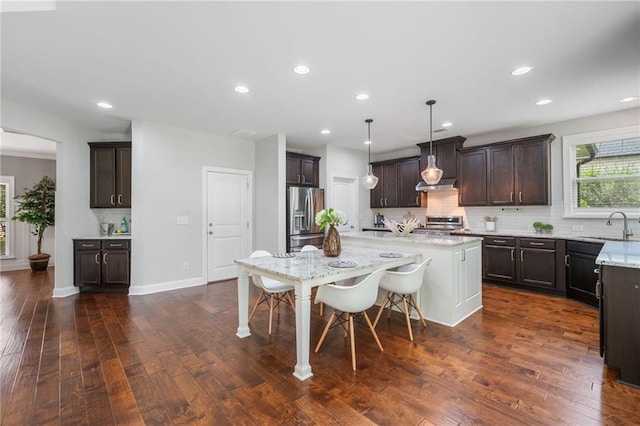 4460 Hunters Walk Way, Cumming, GA 30028 - kitchen featuring stainless steel fridge with ice dispenser, backsplash, dark brown cabinetry, a kitchen bar, and a center island with sink