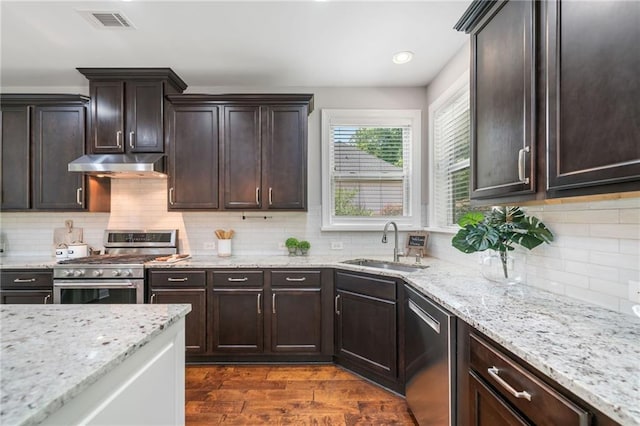 4460 Hunters Walk Way, Cumming, GA 30028 - kitchen featuring appliances with stainless steel finishes, under cabinet range hood, dark brown cabinets, light stone countertops, and decorative backsplash