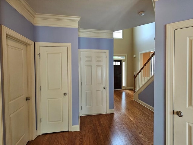 entrance foyer with baseboards, ornamental molding, dark wood finished floors, and stairway