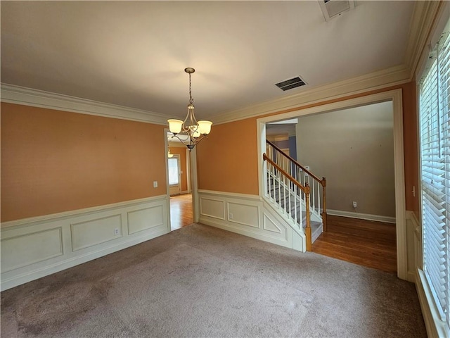 spare room with an inviting chandelier, visible vents, carpet floors, and crown molding