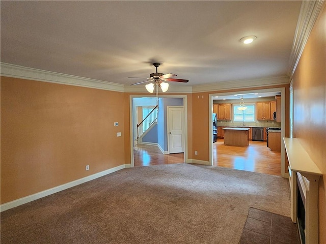 unfurnished living room featuring a ceiling fan, ornamental molding, light colored carpet, and baseboards