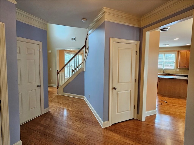 hallway featuring baseboards, dark wood-style flooring, crown molding, and visible vents