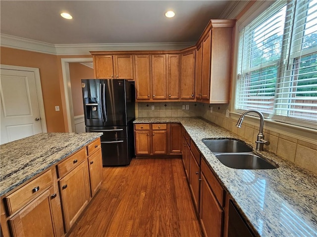 kitchen featuring black refrigerator with ice dispenser, brown cabinetry, dark wood finished floors, a sink, and crown molding