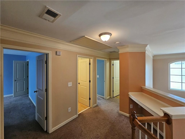 corridor with ornamental molding, baseboards, visible vents, and dark carpet