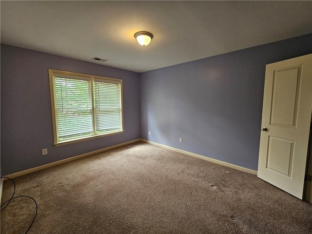 carpeted spare room featuring baseboards and visible vents