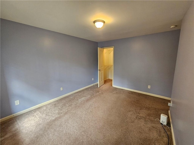 carpeted spare room featuring baseboards