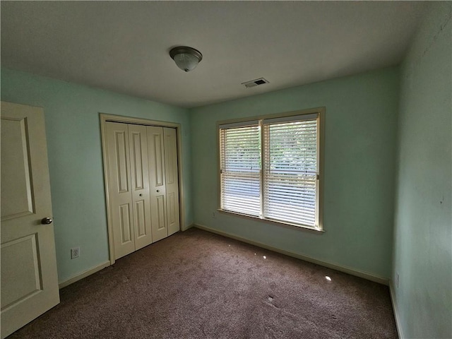 unfurnished bedroom with baseboards, carpet flooring, a closet, and visible vents