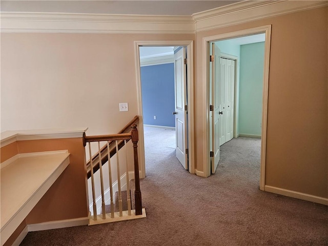 hallway featuring baseboards, ornamental molding, an upstairs landing, and carpet floors