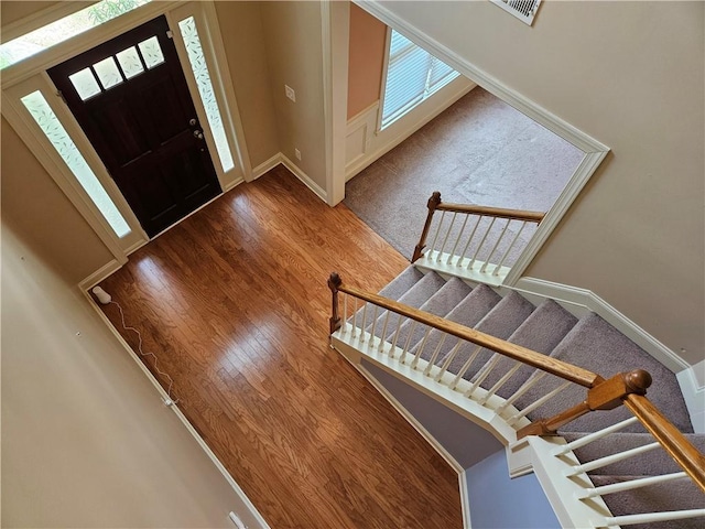 foyer with stairs, baseboards, visible vents, and wood finished floors