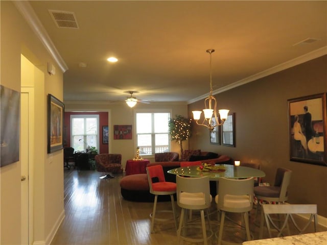 dining area featuring ceiling fan with notable chandelier, dark hardwood / wood-style flooring, and ornamental molding