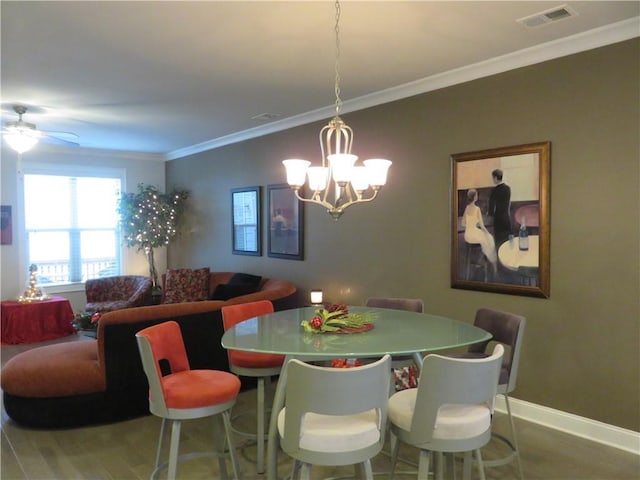 dining room with crown molding, wood-type flooring, and ceiling fan with notable chandelier