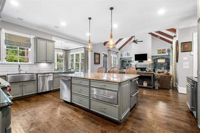 kitchen featuring stainless steel dishwasher, a sink, a kitchen island, and gray cabinetry