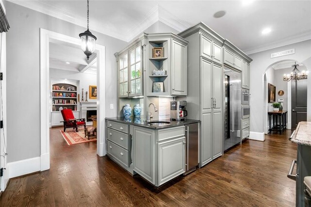 kitchen with crown molding, open shelves, gray cabinets, arched walkways, and a sink