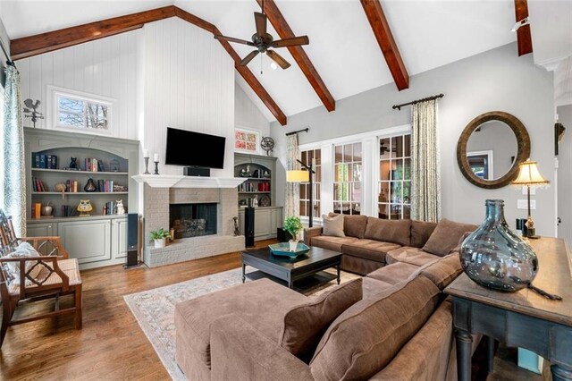 living room with ceiling fan, wood finished floors, high vaulted ceiling, and beamed ceiling