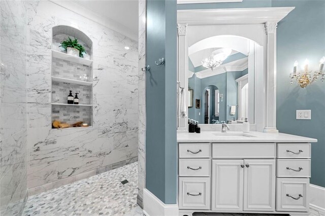 bathroom featuring an inviting chandelier, a marble finish shower, ornamental molding, and vanity