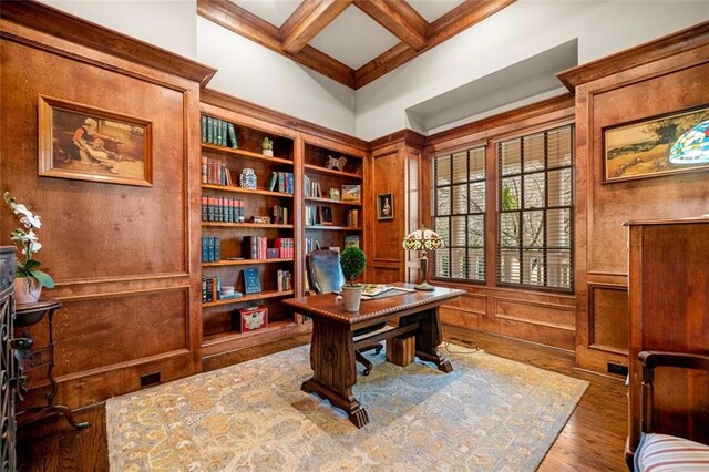 office space with a towering ceiling, beamed ceiling, wood finished floors, and coffered ceiling