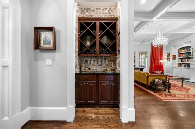 bar with tasteful backsplash, dark wood finished floors, beam ceiling, baseboards, and coffered ceiling