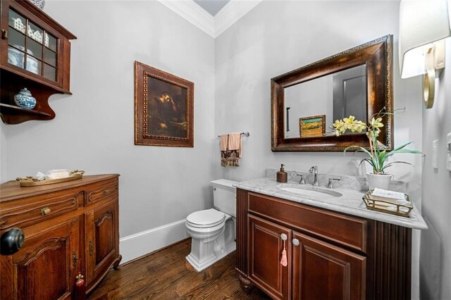 bathroom with crown molding, vanity, wood finished floors, toilet, and baseboards