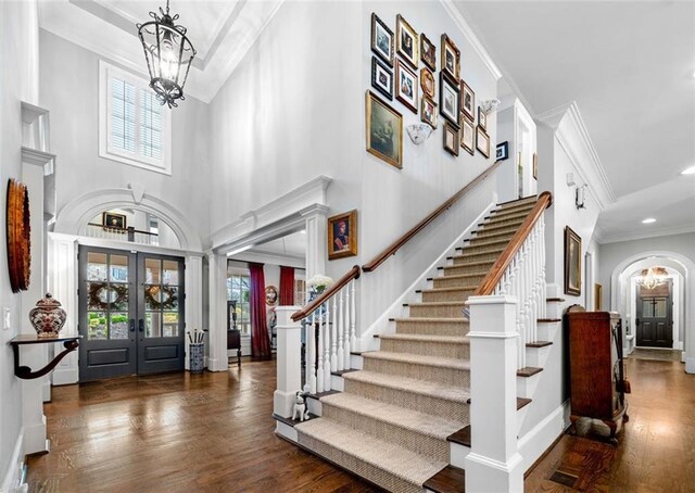foyer with french doors, wood finished floors, a notable chandelier, and stairway