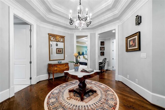 interior space featuring crown molding, a chandelier, baseboards, wood finished floors, and a tray ceiling
