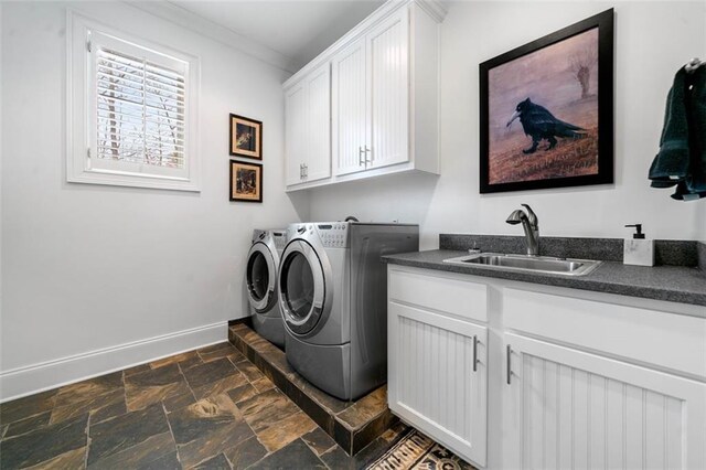 clothes washing area with baseboards, stone finish flooring, a sink, cabinet space, and independent washer and dryer