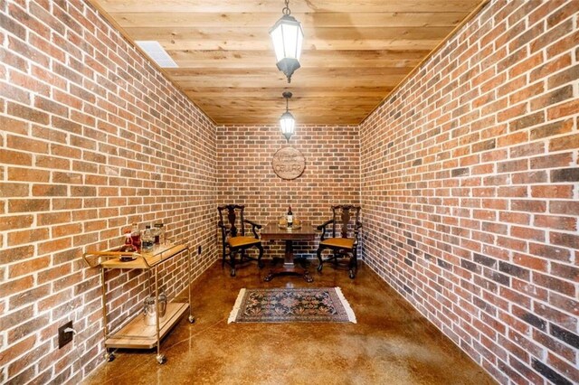 interior space with finished concrete floors, wood ceiling, and brick wall