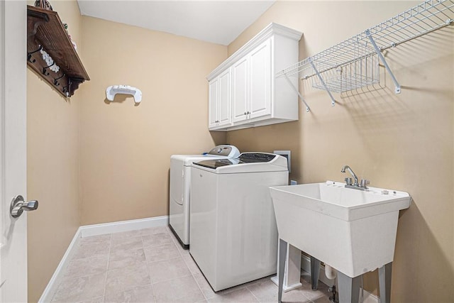 laundry room with baseboards, washing machine and dryer, light tile patterned floors, cabinet space, and a sink