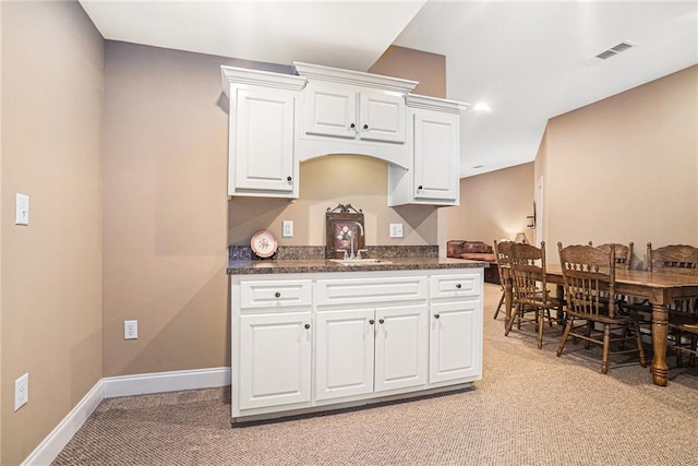 kitchen featuring dark countertops, visible vents, white cabinetry, and a sink