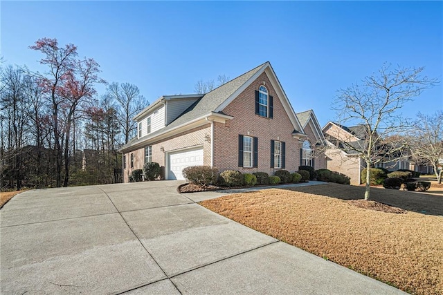 view of side of home featuring brick siding, concrete driveway, and a lawn