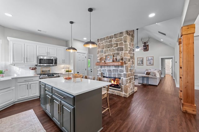 300 Olde Wick Trl, Hoschton, GA 30548 - kitchen with stainless steel microwave, white cabinets, a kitchen bar, dark wood-style floors, and vaulted ceiling