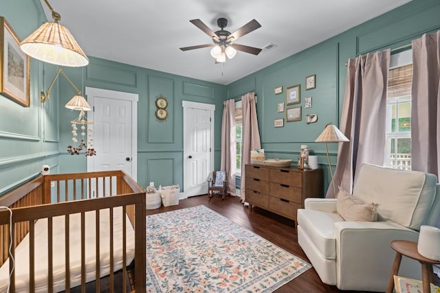 300 Olde Wick Trl, Hoschton, GA 30548 - bedroom featuring a decorative wall, a nursery area, dark wood-style flooring, and a ceiling fan