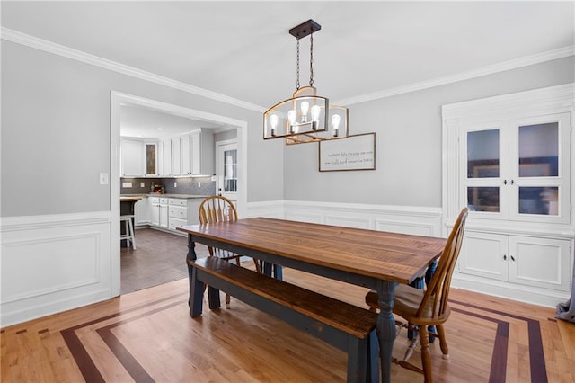 75 Auburn Rd, Auburn, GA 30011 - dining space with crown molding, a chandelier, a wainscoted wall, and light wood finished floors