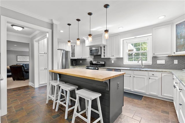 75 Auburn Rd, Auburn, GA 30011 - kitchen featuring wood counters, appliances with stainless steel finishes, stone tile floors, white cabinetry, and ornamental molding
