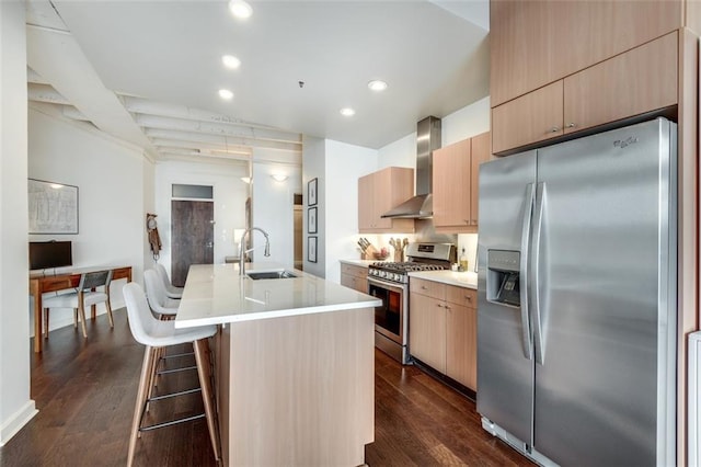 kitchen with sink, appliances with stainless steel finishes, dark hardwood / wood-style floors, an island with sink, and wall chimney range hood