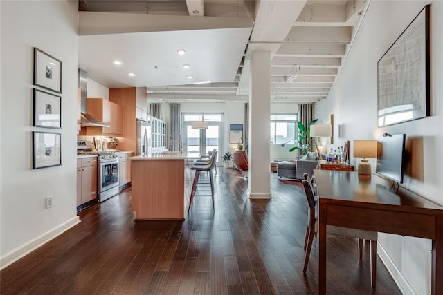 kitchen with appliances with stainless steel finishes, a center island, dark hardwood / wood-style floors, and wall chimney exhaust hood