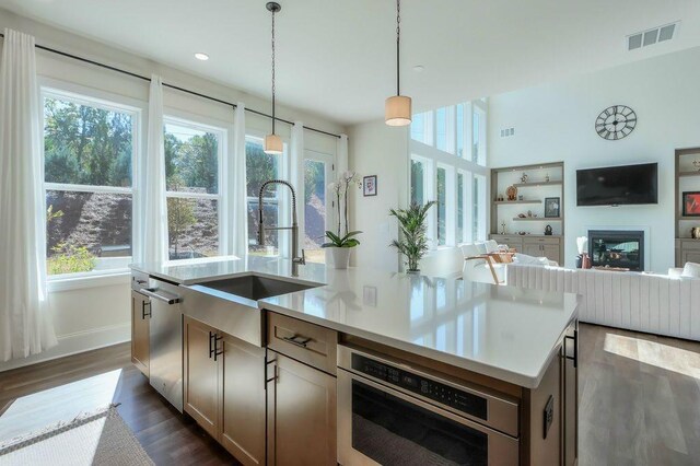 kitchen with sink, appliances with stainless steel finishes, dark hardwood / wood-style floors, hanging light fixtures, and a kitchen island