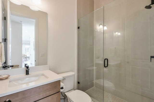 bathroom with a shower with door, vanity, and toilet