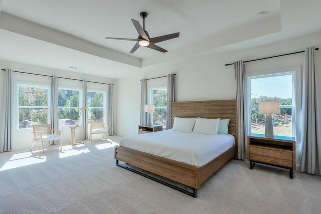 bedroom featuring multiple windows, light colored carpet, and ceiling fan