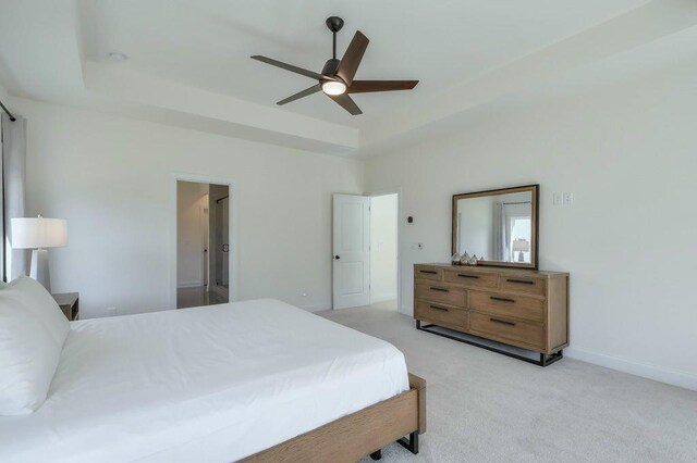 carpeted bedroom with ceiling fan and a tray ceiling