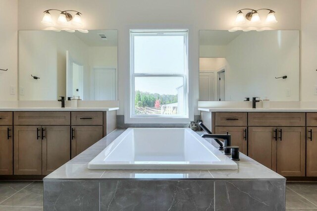 bathroom featuring tile patterned flooring, vanity, and tiled tub