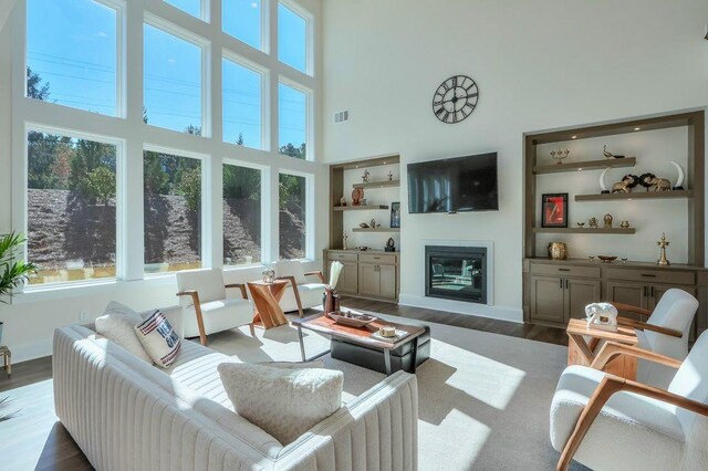 living room with dark hardwood / wood-style flooring, built in features, and a towering ceiling