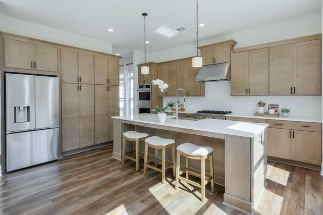 kitchen with appliances with stainless steel finishes, a center island with sink, dark hardwood / wood-style floors, and sink